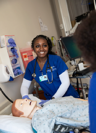 A nursing student stands by a practice dummy